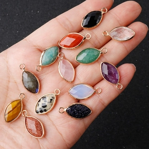 Hand holding assorted marquise-cut crystal pendants with gold-plated copper edging