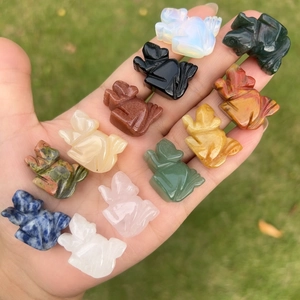 Handheld view of 1-inch hand-carved natural crystal frog figurines in assorted gemstones