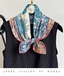 Détail d'un foulard en soie et laine à imprimé jungle tropicale sur robe noire