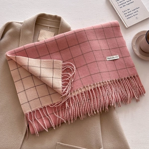 Detail of pink plaid scarf texture with fringes on wool coat and coffee background