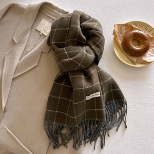 Close-up of dark green plaid scarf with fringe, paired with a beige winter wool coat