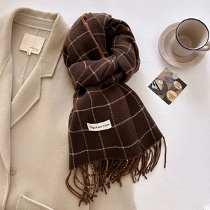 Close-up of brown plaid scarf with tassels, soft cashmere texture and brand label