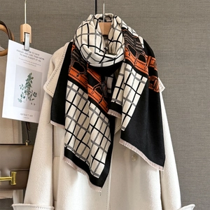 Détail d'une écharpe à motif de cheval avec touches orange sur un manteau en laine