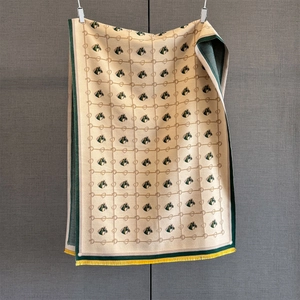Detail of horse head pattern knit scarf with green borders and yellow tassels