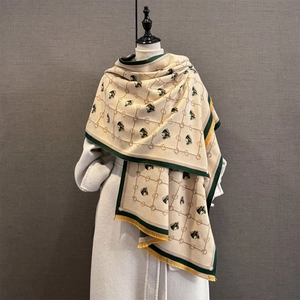 Detail of horse-head jacquard pattern on cream and green cashmere-feel scarf