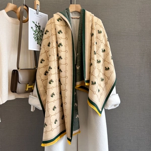 Cashmere horse pattern scarf in beige and green with yellow tassels on coat