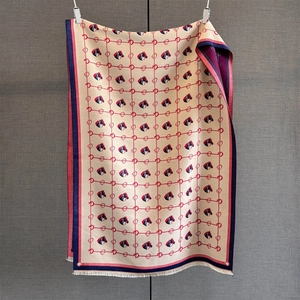 Close-up of beige jacquard scarf featuring red horse patterns and delicate white fringe