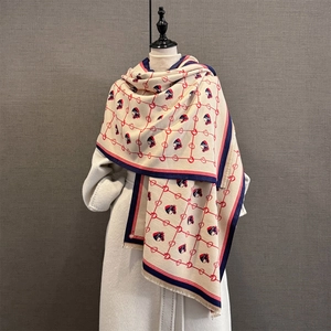 Detail of horse-head jacquard pattern scarf with tassels on white wool coat display