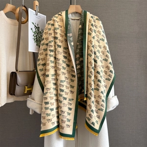 Thick beige winter scarf with green cow pattern, yellow tassels on white coat