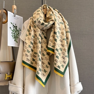 Detail of soft cream scarf with cute cow patterns, yellow tassels and green edges
