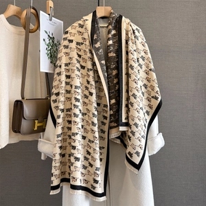 Detail of soft beige scarf with cartoon cow pattern and black tassels on white coat