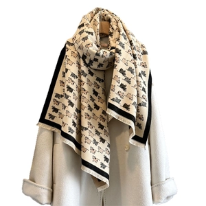 Thick warm autumn scarf with cute cow patterns and white tassels on cream wool coat