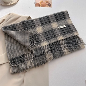 Close-up of thick cashmere-like plaid scarf with vintage tassels and woven label detail