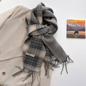 Detail of grey and beige plaid scarf with tassels styled on a beige suit lapel