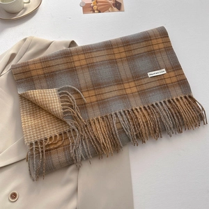 Detail of soft cashmere-like retro plaid scarf with delicate fringe and brand label