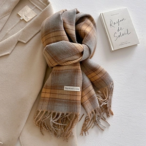 Macro detail of plaid cashmere-like scarf with soft fringes and earth tone patterns