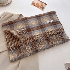 Detailed texture of thick plaid cashmere scarf with soft fringe and stylish label