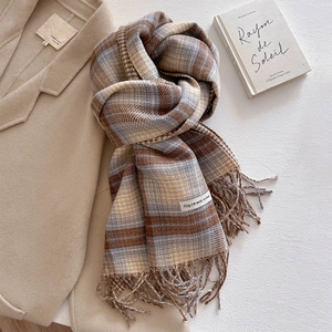 Detail of plaid cashmere scarf with tassels showing soft texture and washing label