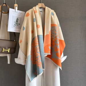 Detailed view of autumn leaf jacquard pattern and fine tassel edges on beige pashmina