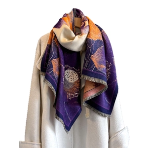 Écharpe jacquard lotus à l'encre violette et orange portée sur un manteau beige