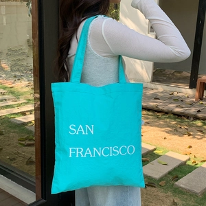 Borsa tote in nylon ciano con stampa San Francisco indossata a spalla all'aperto