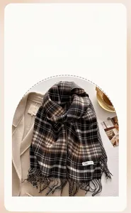 Detail of vintage brown plaid scarf with fringe texture on a white wool coat