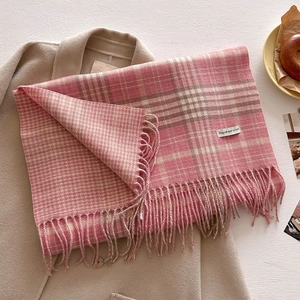 Close-up of pink and beige plaid scarf with tassels on a wool coat with bagel plate
