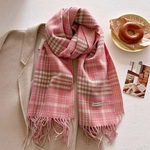 Detail of pink plaid scarf with fringe tassels worn over an oatmeal wool coat