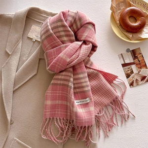 Close-up of pink checkered scarf with soft fringe tassels on a wool coat