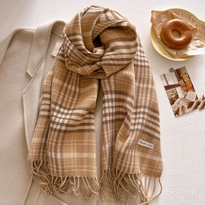 Close-up of soft plaid scarf with fringe on wool coat in warm autumn setting