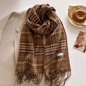 Close-up of thick checkered scarf fabric with tassels and a white origin label