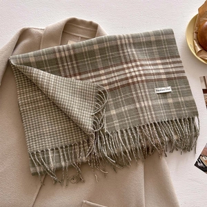 Close-up of green and beige plaid scarf with fringe detail on wool coat background