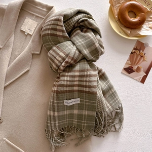 Detail of vintage plaid scarf with soft fringe on beige wool coat and lifestyle decor