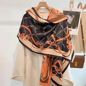 Thick autumn scarf with chain pattern and tassels draped over a white wool coat