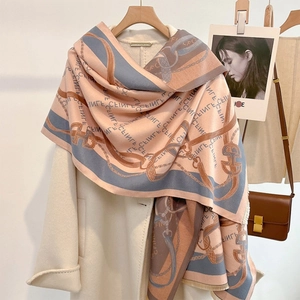 Pink and orange jacquard scarf with horsebit chain motifs styled on a white coat