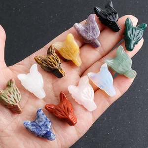 Hand holding assorted natural gemstone wolf head carvings in crystal and tiger eye