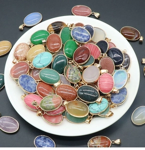 Close-up of mixed natural agate and crystal oval pendants with gold clips on a white plate