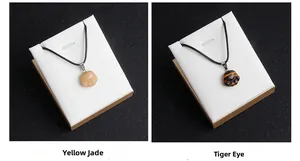 Detail of hand-carved yellow jade and tiger eye cat paw pendants with black cords