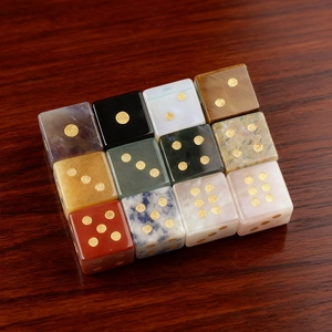 Set of 12 natural gemstone dice including amethyst and tiger eye on a dark wood background