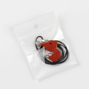 Red natural stone reindeer pendant with black cord shown in transparent plastic packaging