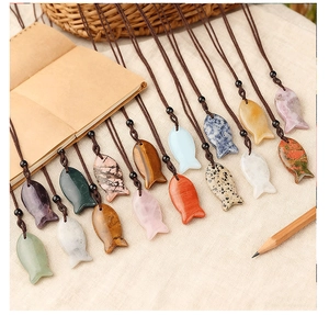 Detailed collection of fish-shaped natural stone pendants on beige linen with rustic props