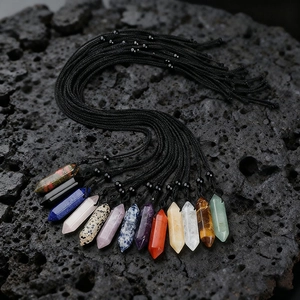 Set of 13 hexagonal natural gemstone crystal pendants with black braided cords on lava rock