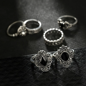 Close-up of bohemian silver rings set with black diamond-shaped and round gemstones