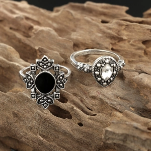 Close-up of vintage silver rings with black oval gemstone and fleur-de-lis engraving