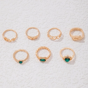 Detailansicht des 7-teiligen Goldring-Sets mit grünen Smaragdsteinen und Herzdesigns