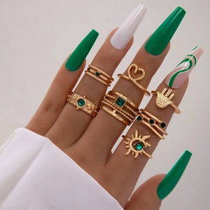 Detail eines 7-teiligen Vintage-Goldring-Sets mit smaragdgrünen Steinen an der Hand