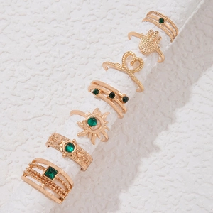 Detail von 7-teiligem Goldring-Set mit smaragdgrünen Steinen und Boho-Motiven