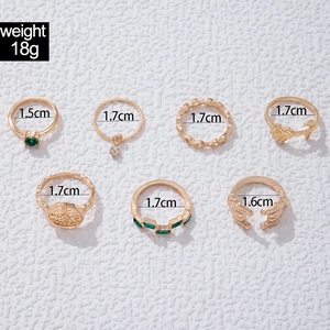 Nahaufnahme von 7-teiligem Vintage-Ring-Set in Gold mit grünen Edelsteinen und Rosendetails