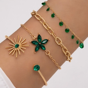 Détail d'un ensemble de quatre bracelets dorés avec pierres émeraude sur le poignet