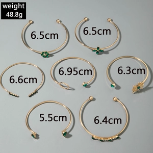 Détail d'un ensemble de bracelets dorés avec pierres vertes et motifs floraux
